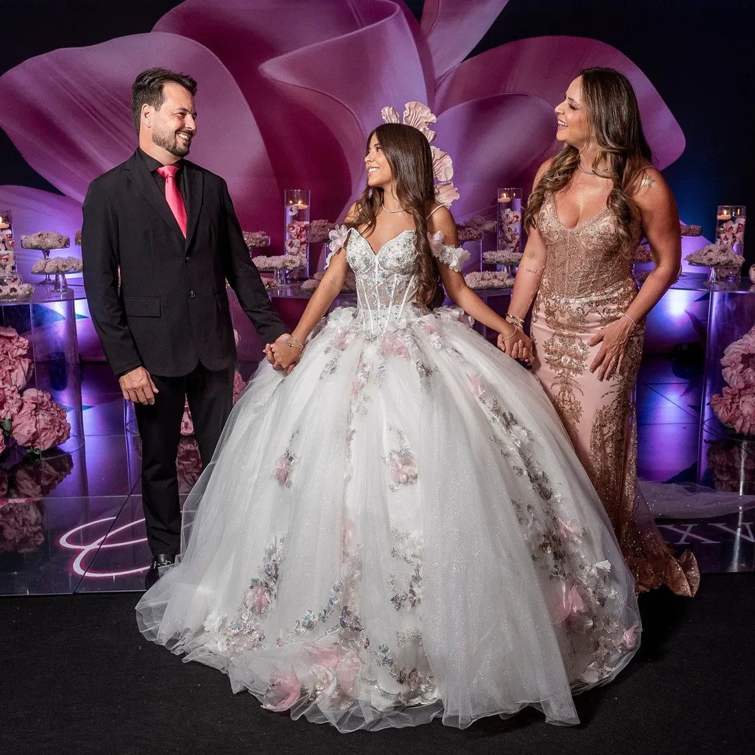 Debutante com a família diante do cenário da festa de 15 anos