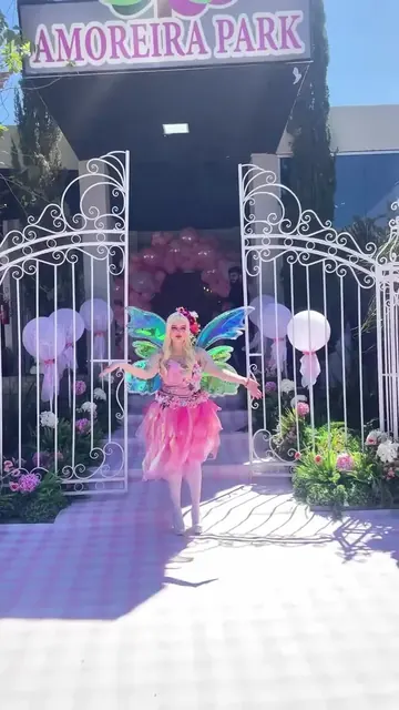 Entrada de festa encantada com portal, flores e personagem fada