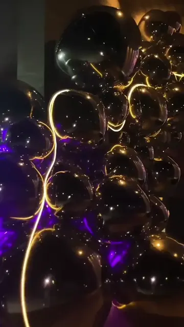 Instalação de balões pretos iluminados em uma festa